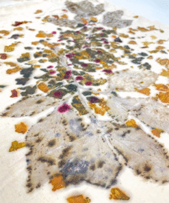 Lähivaade taimetrükist: detailsed lehemustrid ja looduslikud värvid heledal kangal.